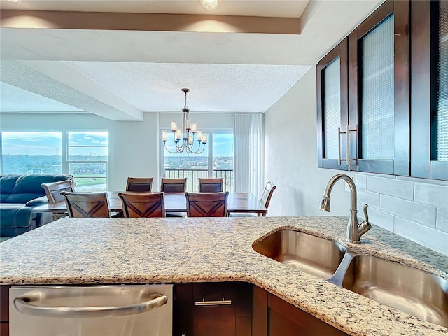 kitchen with backsplash, a wealth of natural light, sink, decorative light fixtures, and a chandelier