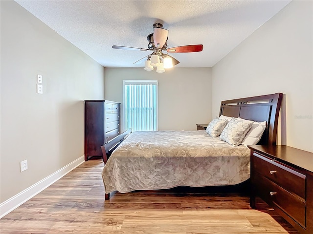 bedroom featuring ceiling fan, a textured ceiling, and light wood-type flooring