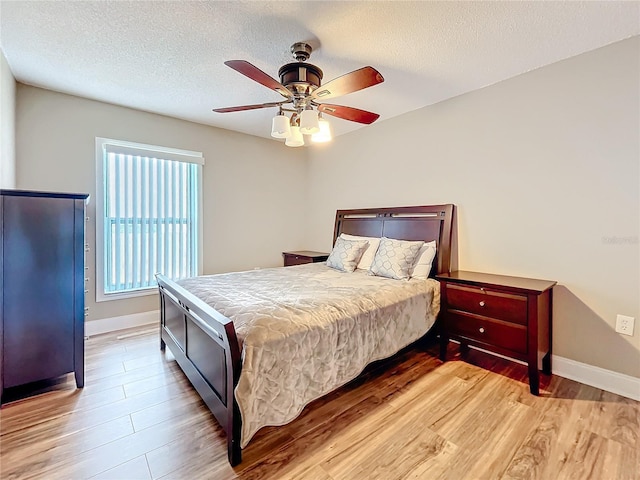 bedroom with a textured ceiling, light hardwood / wood-style flooring, and ceiling fan