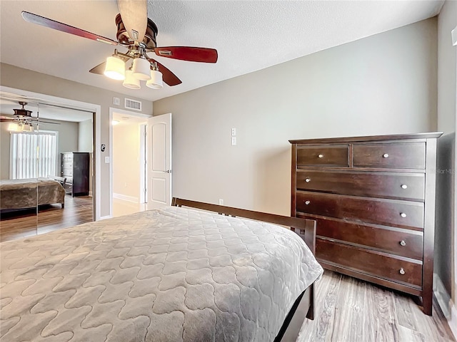 bedroom with ceiling fan, a closet, a textured ceiling, and light wood-type flooring