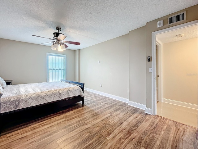 bedroom featuring a textured ceiling, light hardwood / wood-style flooring, and ceiling fan