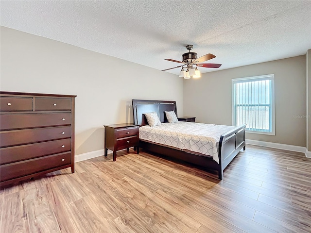 bedroom with ceiling fan, light hardwood / wood-style floors, and a textured ceiling