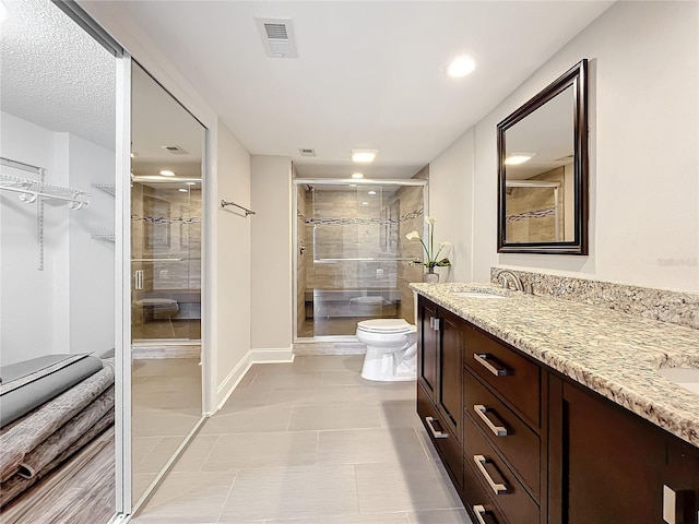 bathroom with tile patterned floors, a shower with door, vanity, and toilet