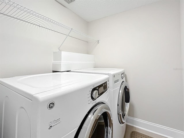 laundry area with washer and clothes dryer and a textured ceiling