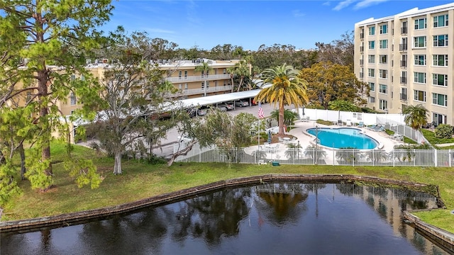 view of pool with a lawn and a water view