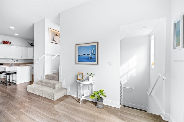 stairs featuring sink and hardwood / wood-style flooring