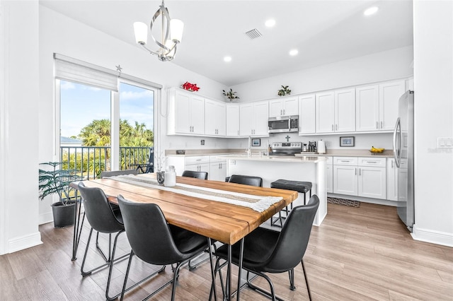 dining space with light hardwood / wood-style floors and an inviting chandelier