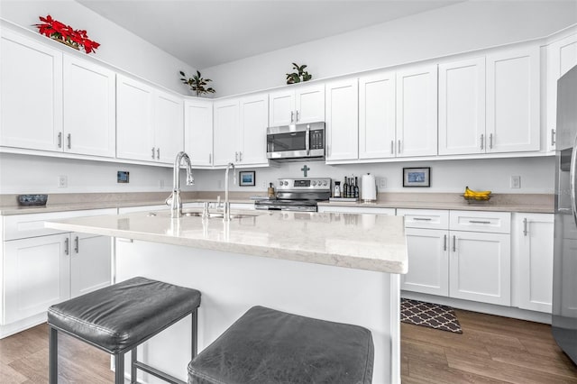 kitchen with white cabinetry, sink, light stone counters, and appliances with stainless steel finishes