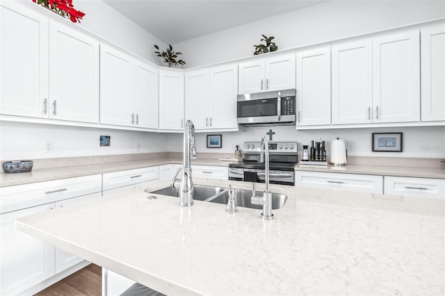 kitchen featuring light stone counters, stainless steel appliances, white cabinetry, and sink