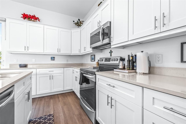 kitchen featuring appliances with stainless steel finishes, light stone counters, sink, dark hardwood / wood-style floors, and white cabinetry