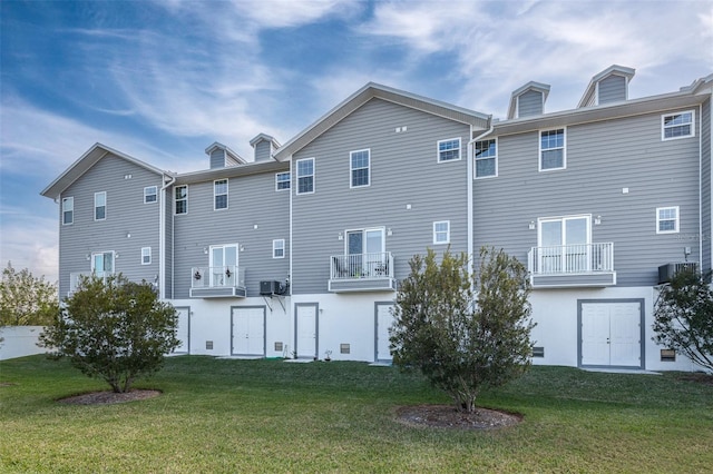 rear view of house featuring a yard, a balcony, and cooling unit