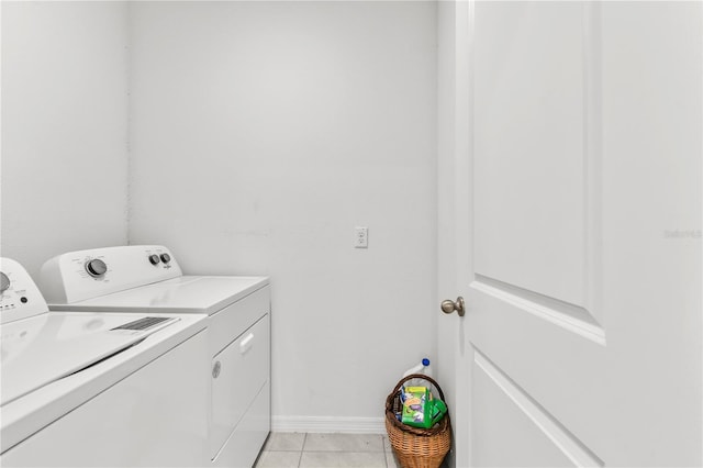 laundry area with washing machine and clothes dryer and light tile patterned floors