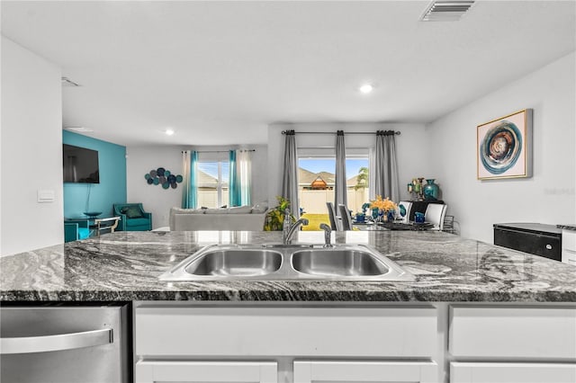 kitchen featuring stainless steel dishwasher, white cabinetry, and sink