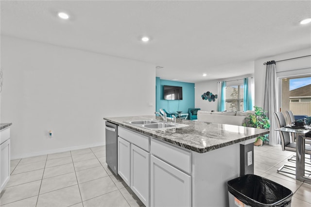 kitchen featuring stainless steel dishwasher, an island with sink, light tile patterned floors, white cabinetry, and sink