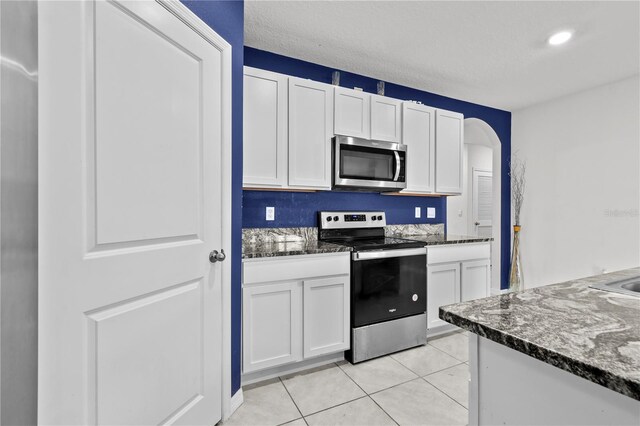 kitchen featuring appliances with stainless steel finishes, light tile patterned floors, and white cabinetry