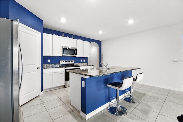 kitchen featuring an island with sink, white cabinetry, appliances with stainless steel finishes, a kitchen breakfast bar, and sink