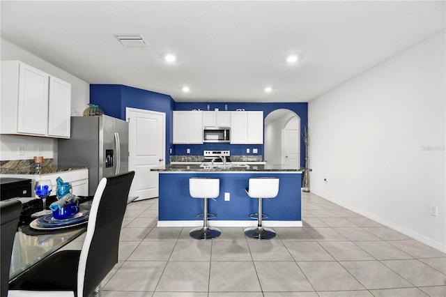 kitchen with a kitchen breakfast bar, a center island, white cabinetry, and appliances with stainless steel finishes