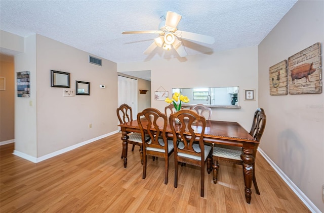 dining room featuring light wood finished floors, visible vents, and a textured ceiling