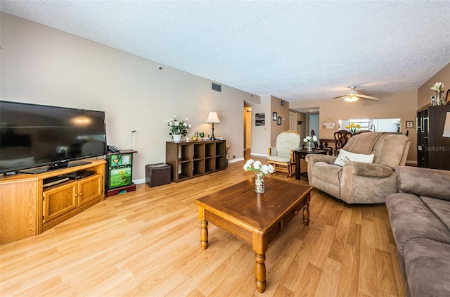 living room with visible vents, a ceiling fan, a textured ceiling, light wood-style floors, and baseboards