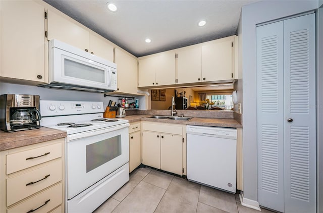 kitchen featuring sink, white appliances, light tile patterned floors, and cream cabinets