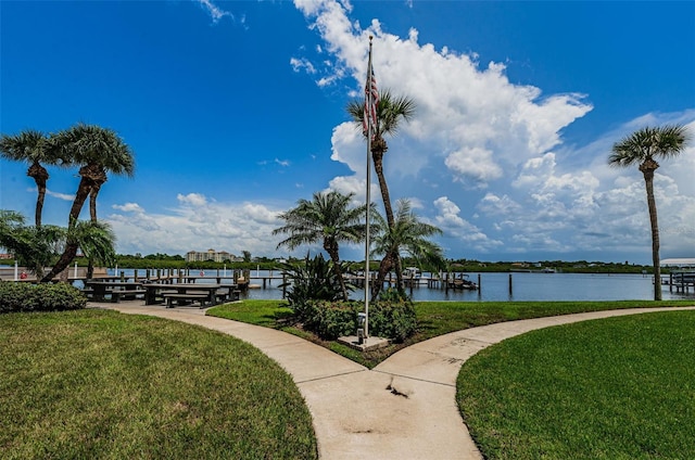 view of property's community with a boat dock, a yard, and a water view