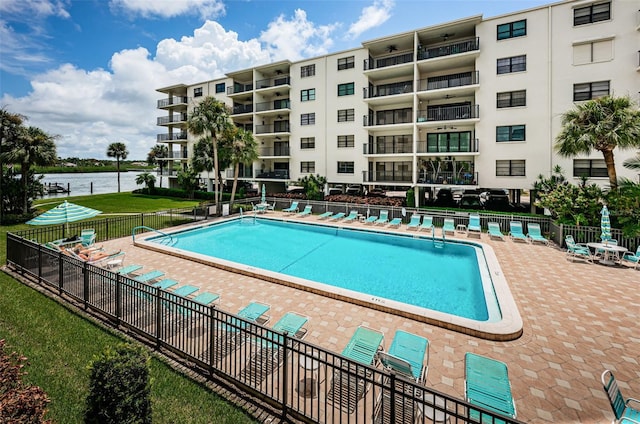 pool featuring a patio, a yard, fence, and a water view