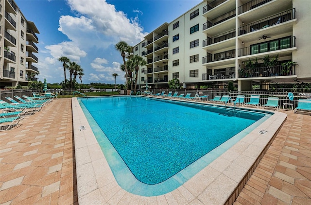 community pool with a patio area and fence