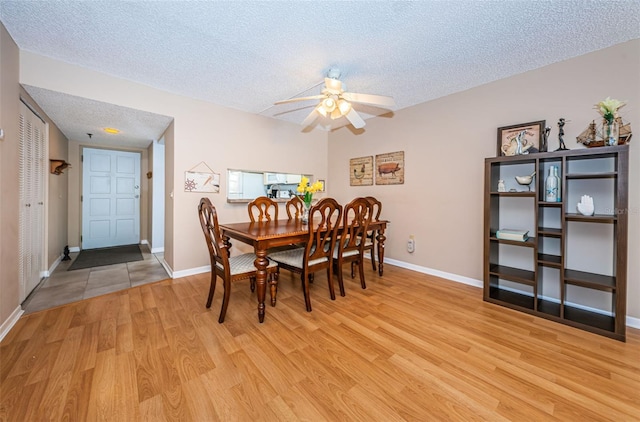 dining area with light hardwood / wood-style floors, a textured ceiling, and ceiling fan