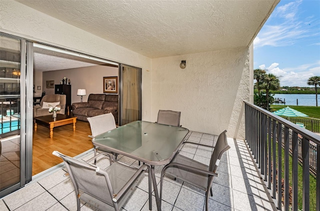 balcony featuring outdoor dining space and a water view