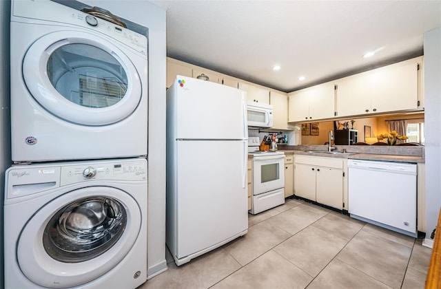 kitchen featuring sink, white cabinets, light tile patterned floors, white appliances, and stacked washer / dryer