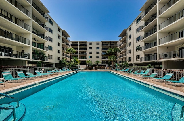 community pool with a patio area and fence