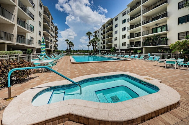 pool featuring a patio, a hot tub, and fence