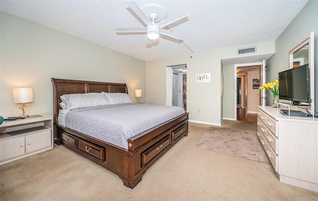 bedroom featuring light carpet, visible vents, a textured ceiling, and a ceiling fan