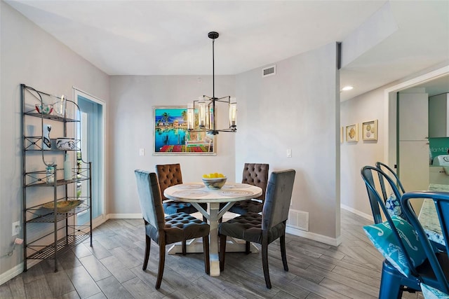 dining room with a chandelier, visible vents, baseboards, and wood finished floors