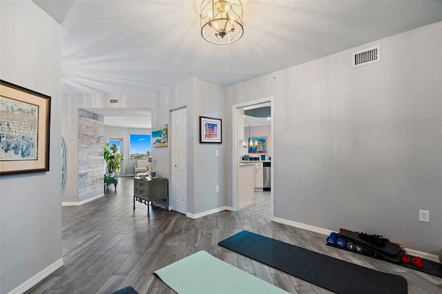 exercise area featuring visible vents, baseboards, an inviting chandelier, and wood finished floors