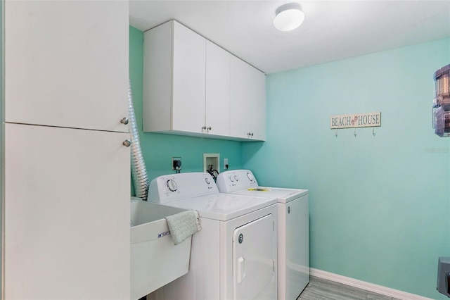 laundry room with baseboards, light wood finished floors, cabinet space, a sink, and independent washer and dryer