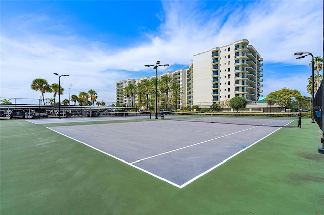 view of tennis court with community basketball court and fence