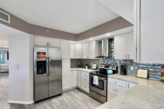 kitchen featuring visible vents, light stone counters, appliances with stainless steel finishes, wall chimney range hood, and decorative backsplash