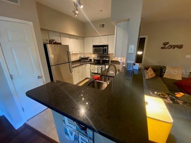 kitchen featuring white cabinetry, sink, stainless steel appliances, backsplash, and kitchen peninsula