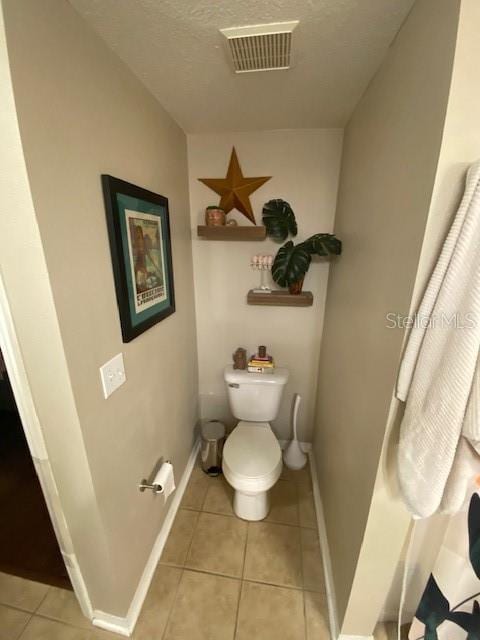 bathroom featuring tile patterned flooring, a textured ceiling, and toilet