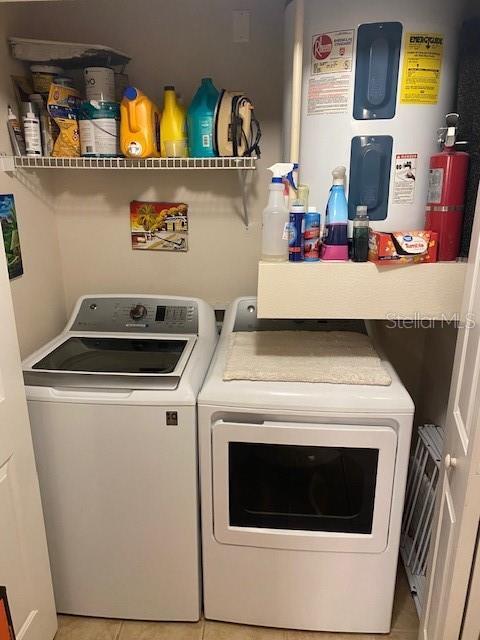 laundry area featuring separate washer and dryer, water heater, and light tile patterned floors