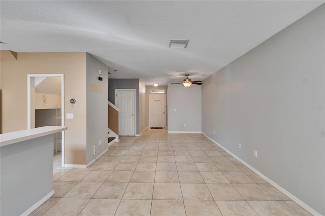 tiled empty room with ceiling fan and a textured ceiling