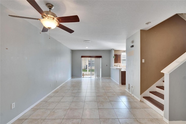 unfurnished living room with a textured ceiling, ceiling fan, and light tile patterned floors