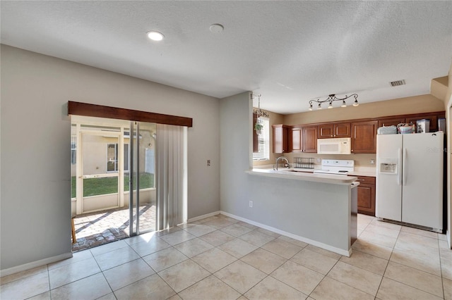 kitchen with white appliances, kitchen peninsula, light tile patterned floors, sink, and decorative light fixtures