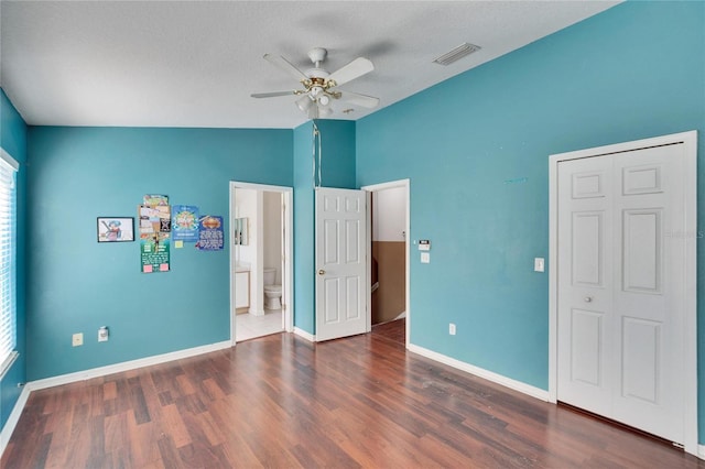 unfurnished bedroom featuring ceiling fan, dark wood-type flooring, connected bathroom, and a textured ceiling