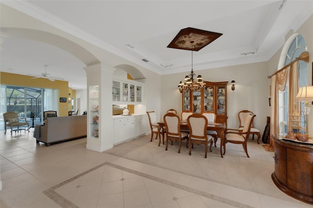 dining space featuring light tile patterned floors, crown molding, ceiling fan with notable chandelier, and a tray ceiling