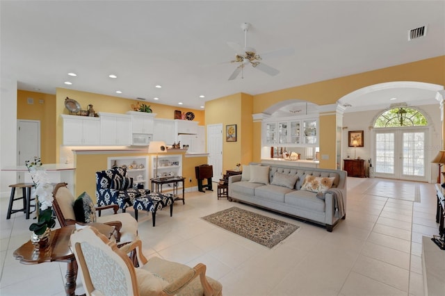 tiled living room featuring french doors, decorative columns, and ceiling fan