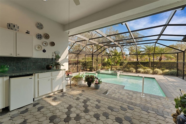 view of swimming pool with a patio, glass enclosure, an in ground hot tub, and area for grilling