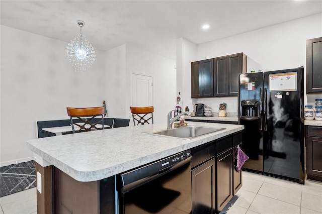 kitchen with decorative light fixtures, light tile patterned floors, black appliances, dark brown cabinets, and a center island with sink