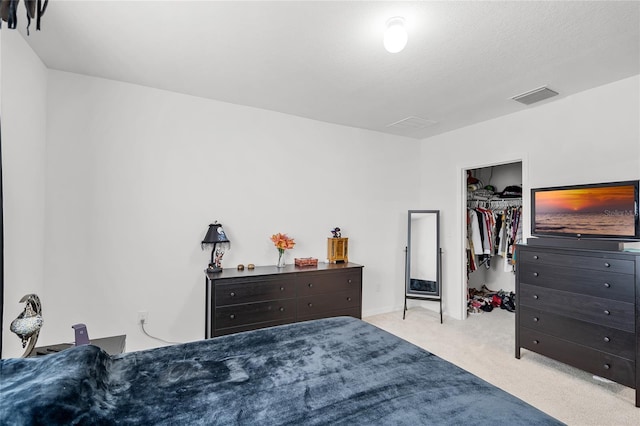 bedroom with light carpet, a walk in closet, a closet, and a textured ceiling